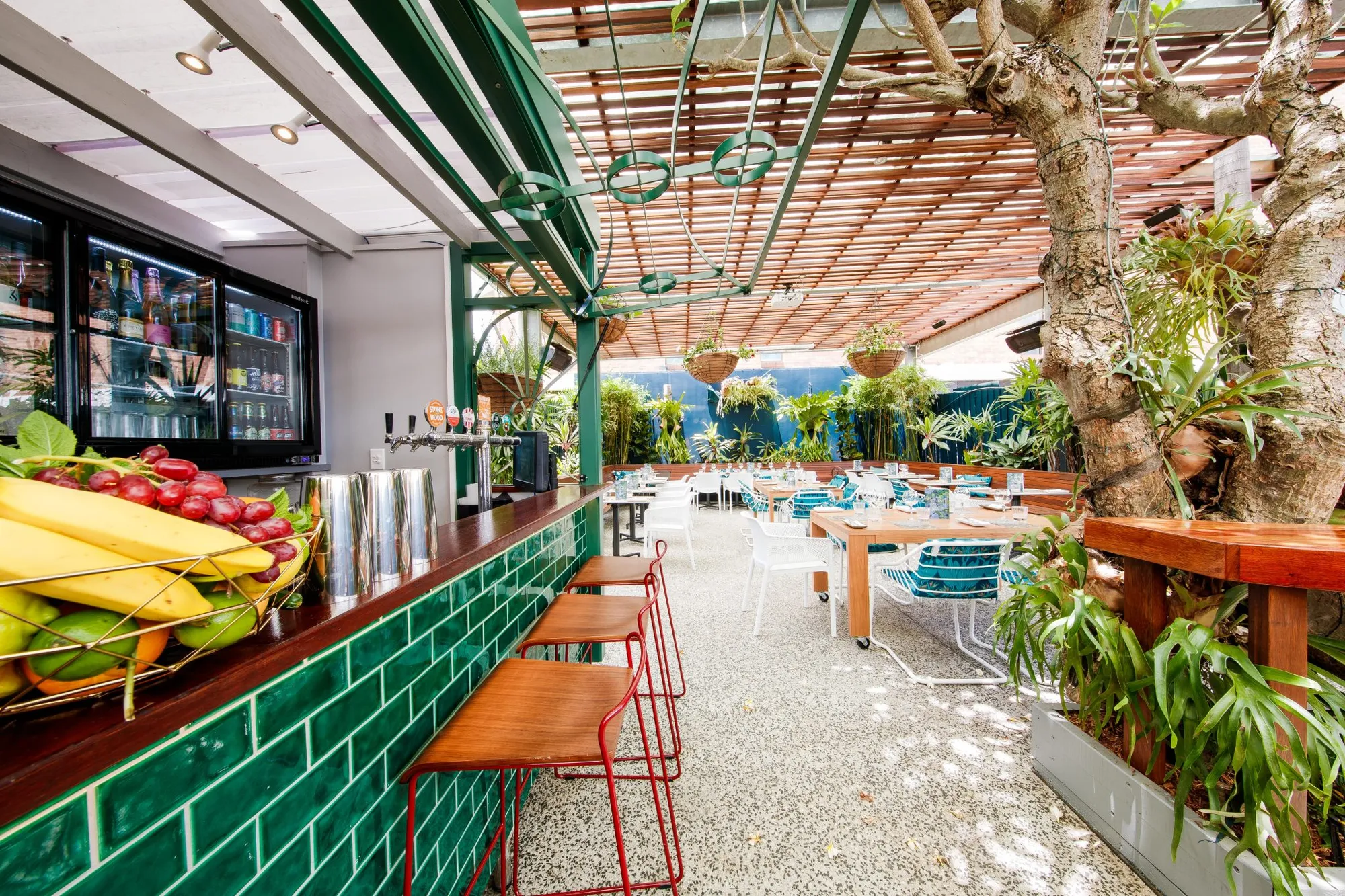 Beer garden bar with green tiles and red stools